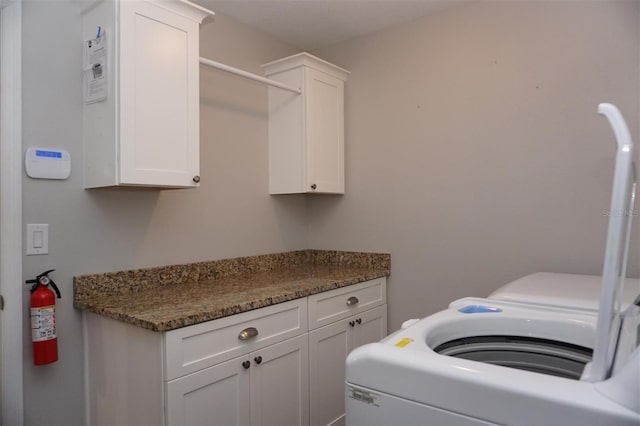 clothes washing area featuring cabinets and washing machine and clothes dryer