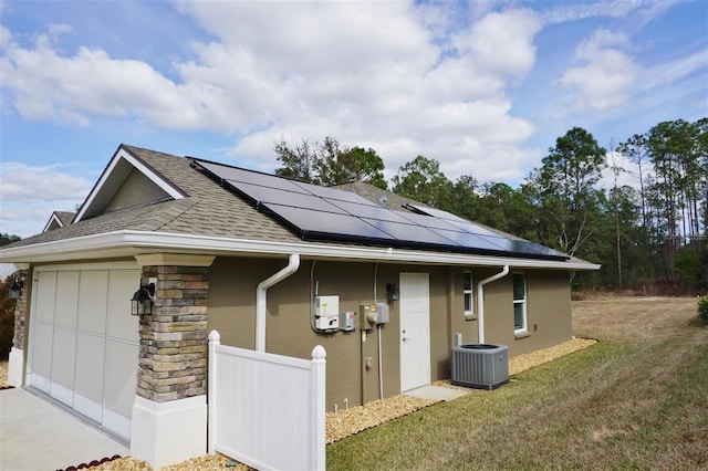 view of side of property with solar panels, a yard, and central air condition unit