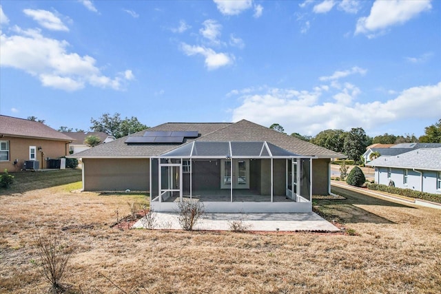 back of property featuring a yard, central AC, and solar panels