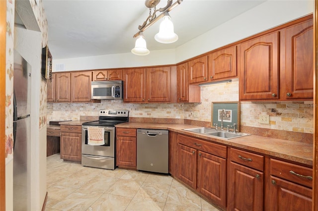 kitchen featuring tasteful backsplash, sink, stainless steel appliances, and hanging light fixtures