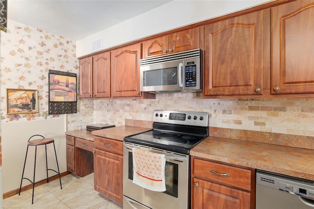 kitchen with tasteful backsplash, appliances with stainless steel finishes, and light tile patterned floors