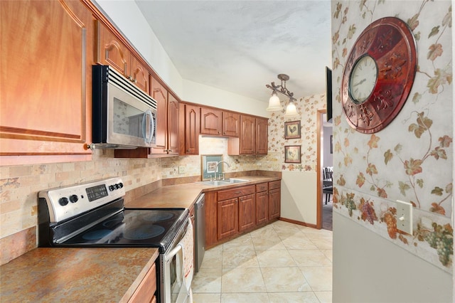 kitchen with sink, hanging light fixtures, light tile patterned floors, stainless steel appliances, and decorative backsplash