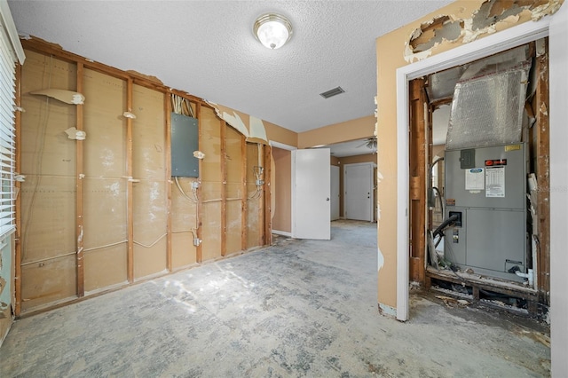 basement featuring heating unit, electric panel, and a textured ceiling