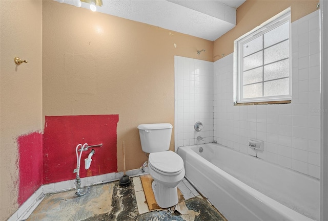 bathroom featuring tiled shower / bath, toilet, and a textured ceiling