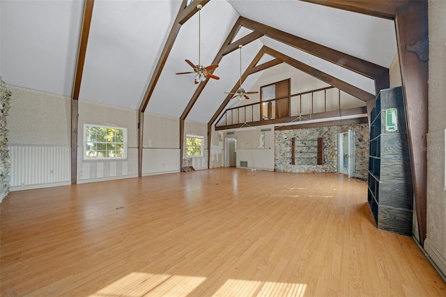 unfurnished living room with wood-type flooring, high vaulted ceiling, ceiling fan, and beam ceiling