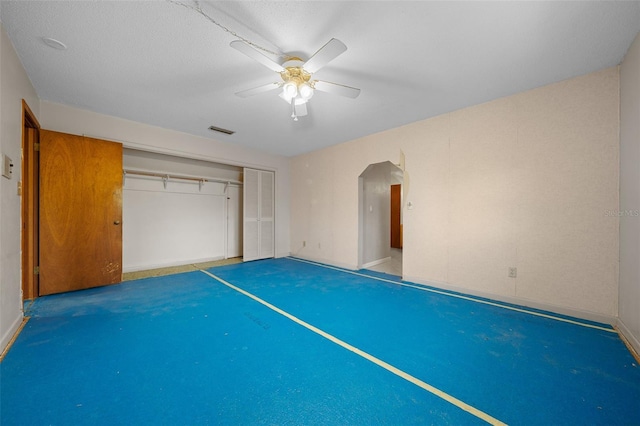 unfurnished bedroom with ceiling fan and a closet