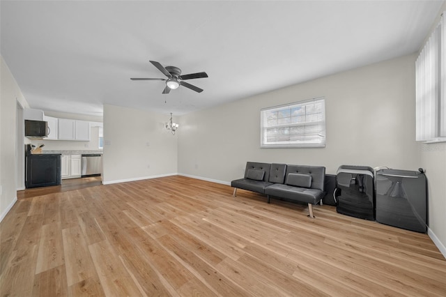 unfurnished living room featuring ceiling fan with notable chandelier and light hardwood / wood-style floors