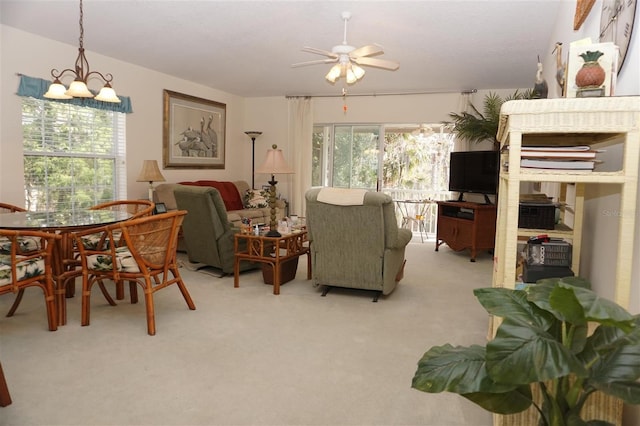 carpeted living room featuring ceiling fan with notable chandelier