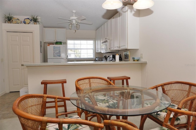 kitchen with white cabinetry, white appliances, kitchen peninsula, and ceiling fan