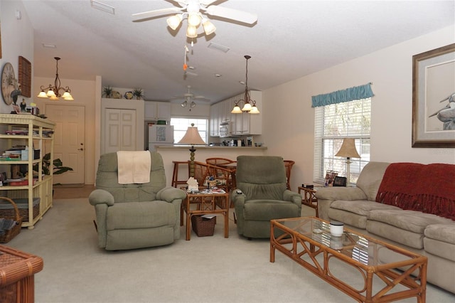 carpeted living room featuring lofted ceiling and ceiling fan with notable chandelier