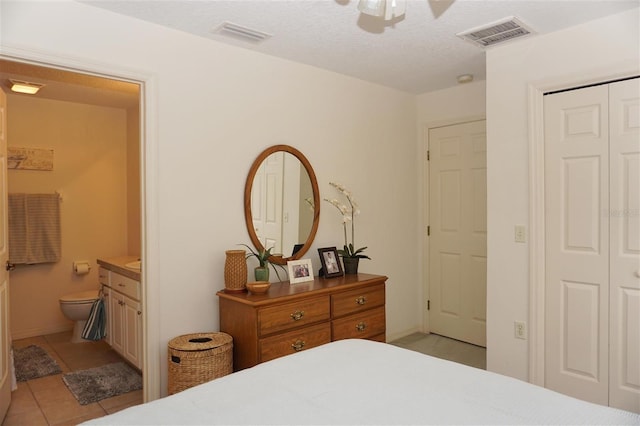 tiled bedroom featuring ceiling fan, connected bathroom, a textured ceiling, and a closet