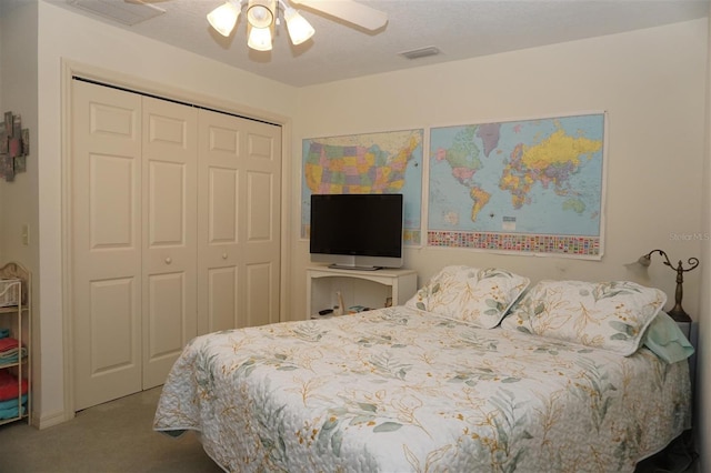 carpeted bedroom with ceiling fan, a closet, and a textured ceiling