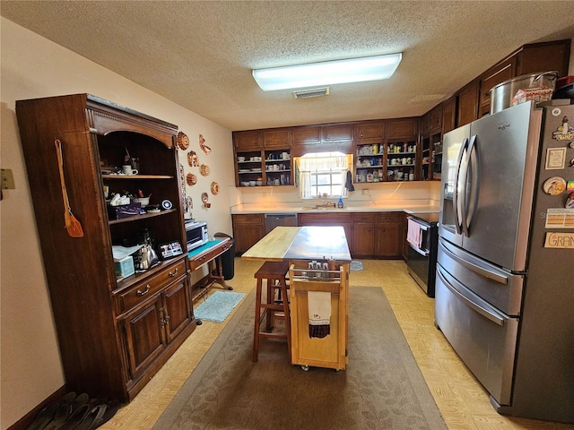 kitchen with a kitchen island, appliances with stainless steel finishes, a breakfast bar, and a textured ceiling