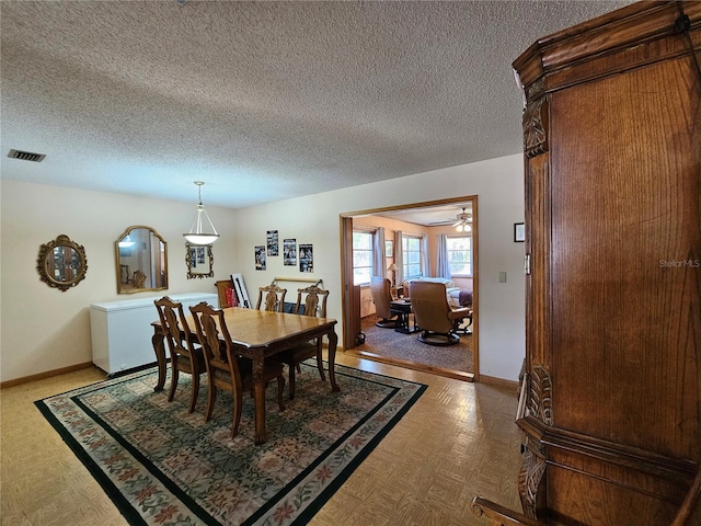 dining room featuring ceiling fan, parquet flooring, and a textured ceiling