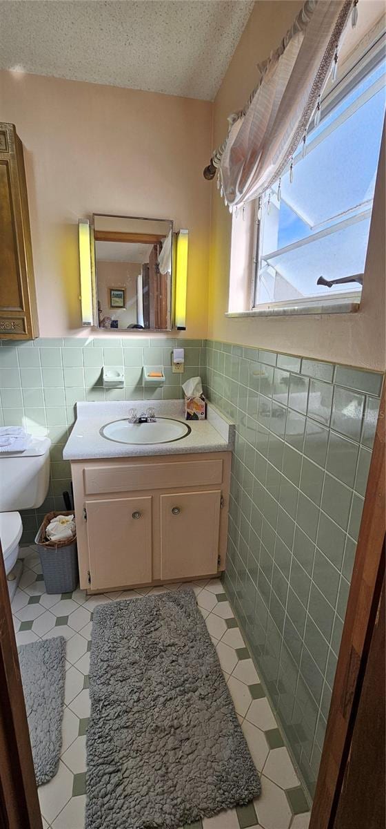 bathroom with vanity, tile walls, a textured ceiling, and toilet