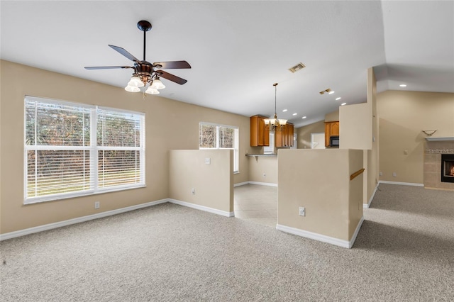 kitchen with light carpet, a tiled fireplace, vaulted ceiling, and plenty of natural light