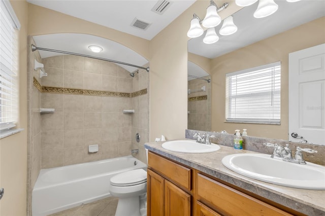 full bathroom with tile patterned flooring, tiled shower / bath, vanity, and toilet