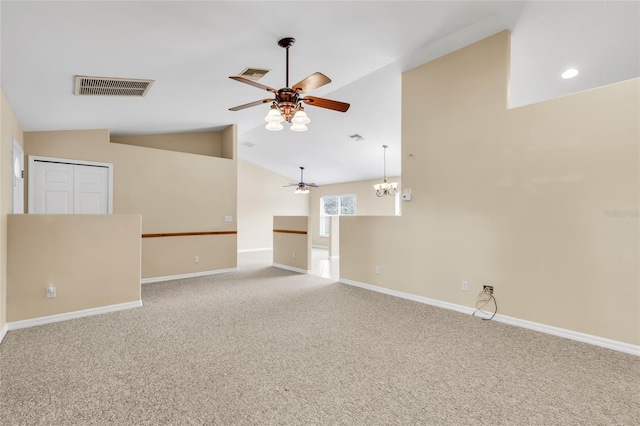 spare room featuring ceiling fan with notable chandelier, carpet floors, and vaulted ceiling