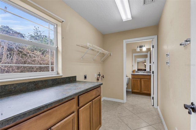 laundry area featuring sink, washer hookup, a textured ceiling, light tile patterned flooring, and hookup for an electric dryer