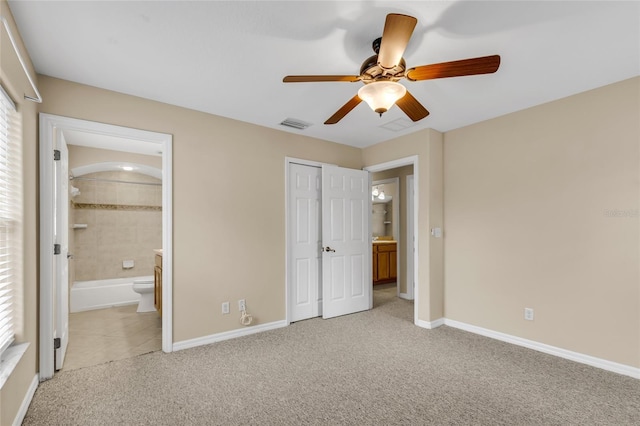 unfurnished bedroom with light carpet, a closet, ceiling fan, and ensuite bathroom