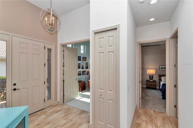 foyer featuring a notable chandelier, a textured ceiling, and light wood-type flooring