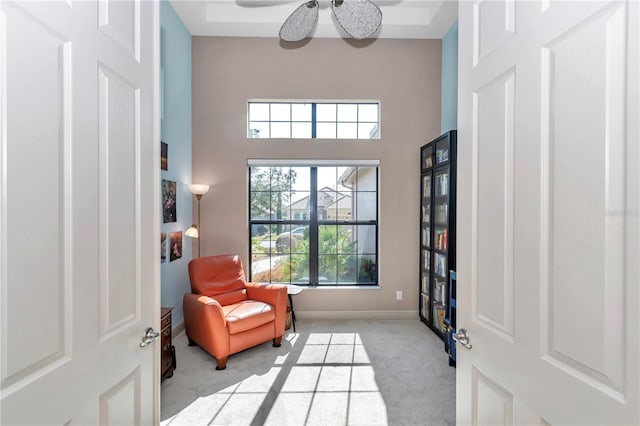 sitting room featuring a towering ceiling and light carpet