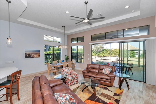 living room featuring light hardwood / wood-style flooring, a textured ceiling, and a tray ceiling