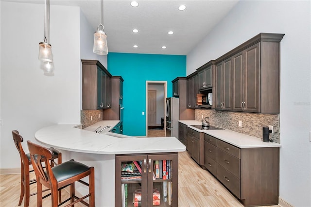 kitchen with pendant lighting, a breakfast bar, dark brown cabinetry, and kitchen peninsula