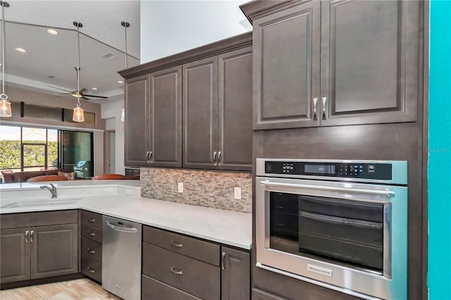 kitchen featuring sink, stainless steel oven, dark brown cabinetry, and decorative backsplash