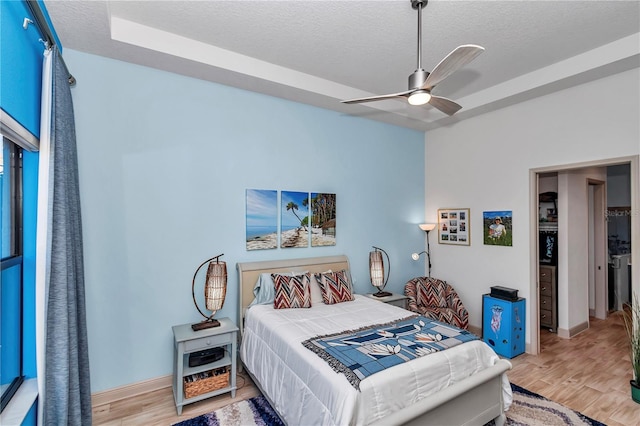 bedroom with ceiling fan, a textured ceiling, and light wood-type flooring