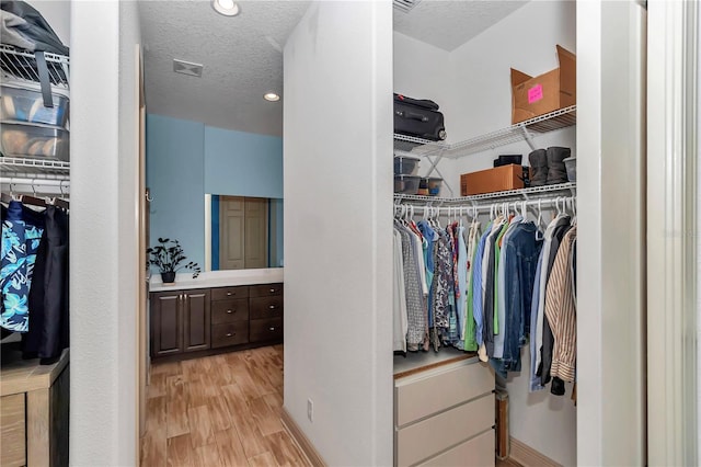 walk in closet with light hardwood / wood-style floors