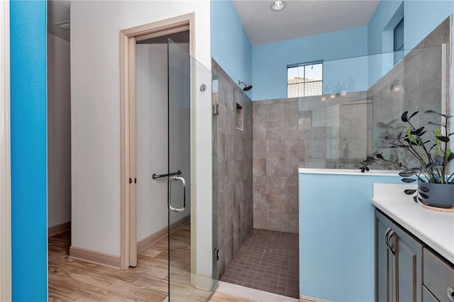 bathroom featuring hardwood / wood-style floors, an enclosed shower, and a textured ceiling