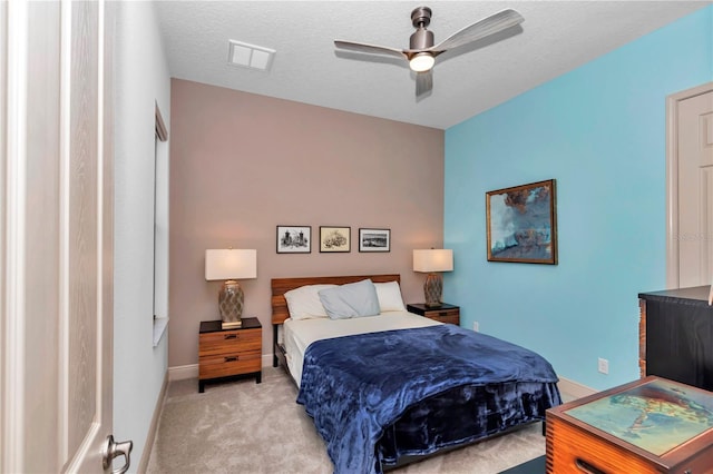 bedroom featuring ceiling fan, light carpet, and a textured ceiling