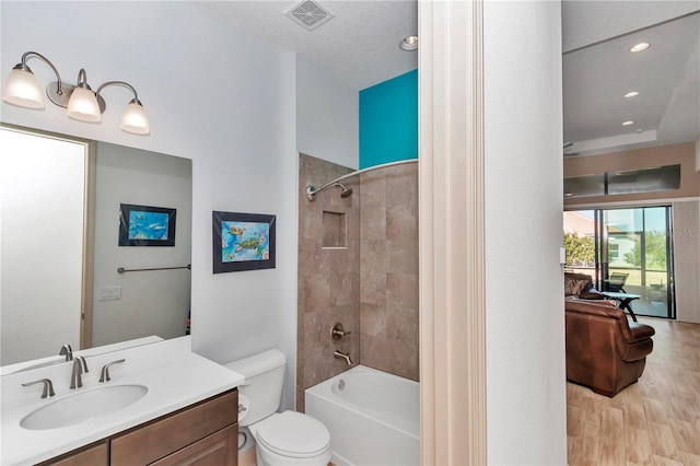 full bathroom with vanity, toilet, tiled shower / bath combo, and hardwood / wood-style floors