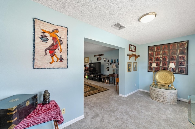 hallway featuring carpet flooring and a textured ceiling