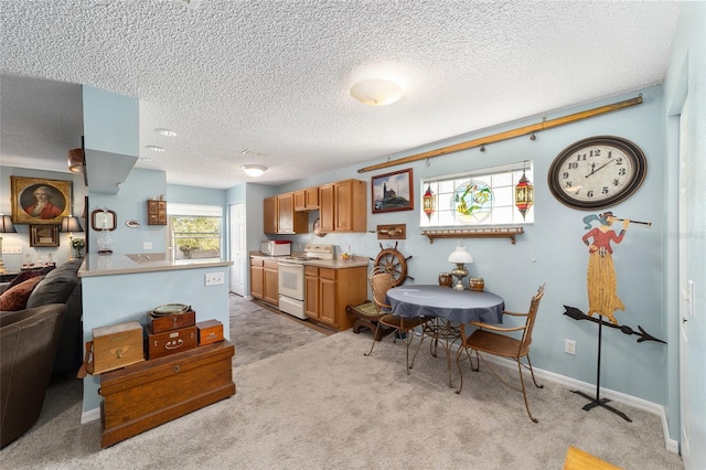 kitchen featuring electric range, light colored carpet, kitchen peninsula, and a textured ceiling