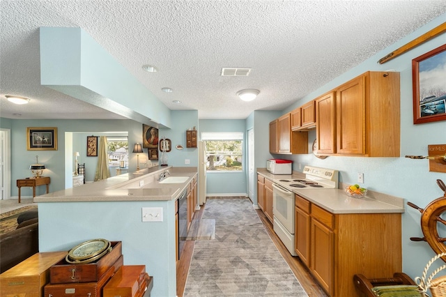 kitchen with sink, white appliances, kitchen peninsula, and a textured ceiling