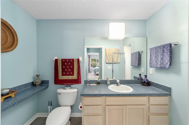 bathroom with vanity, toilet, and a textured ceiling