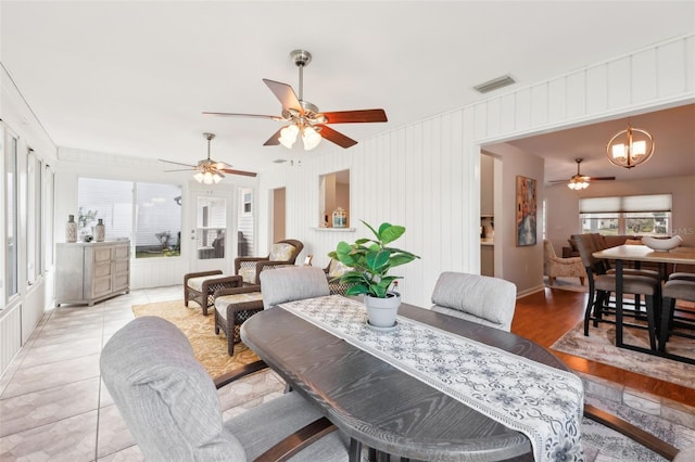 dining room with ceiling fan with notable chandelier, a healthy amount of sunlight, and light tile patterned flooring