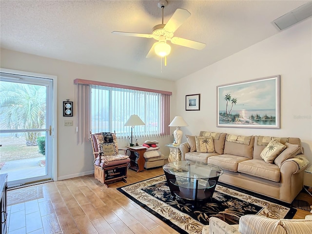 living room featuring ceiling fan, lofted ceiling, light hardwood / wood-style floors, and a textured ceiling