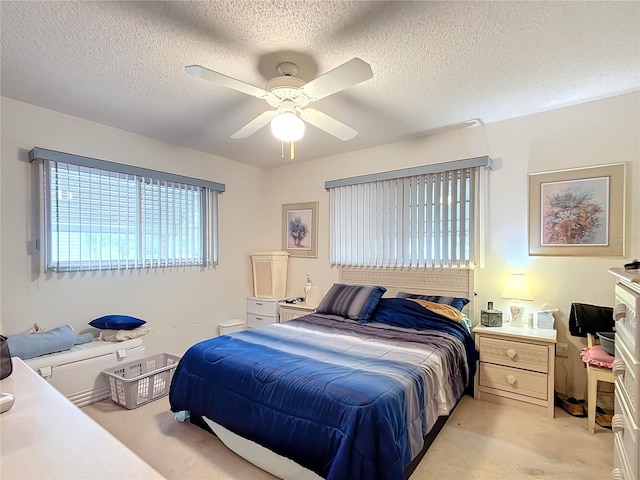 bedroom featuring light carpet, a textured ceiling, and ceiling fan