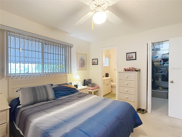 bedroom with ensuite bath, ceiling fan, a textured ceiling, a walk in closet, and a closet