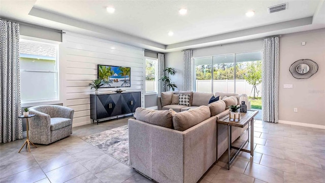 tiled living room featuring a tray ceiling