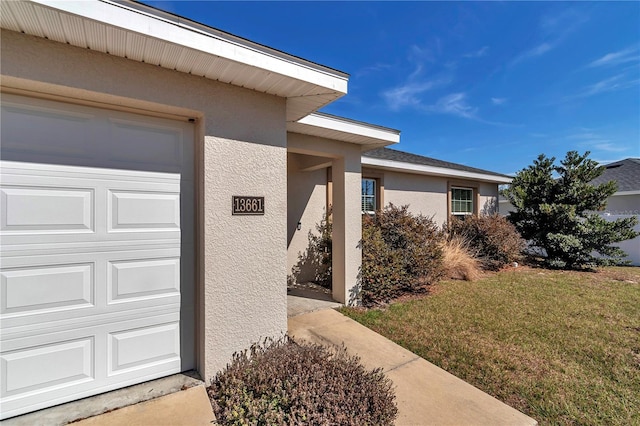 property entrance with a garage and a lawn