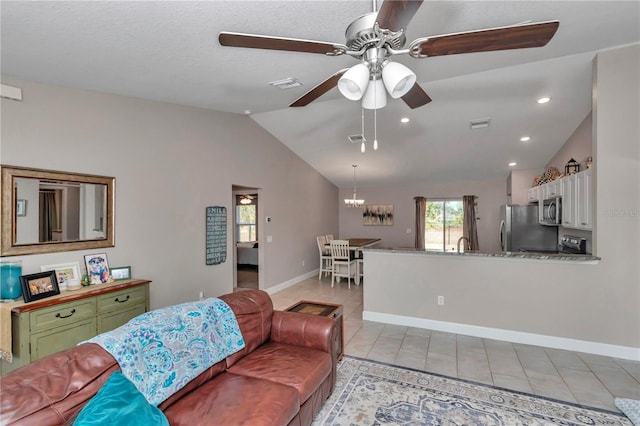 living room with light tile patterned flooring, lofted ceiling, sink, and ceiling fan with notable chandelier