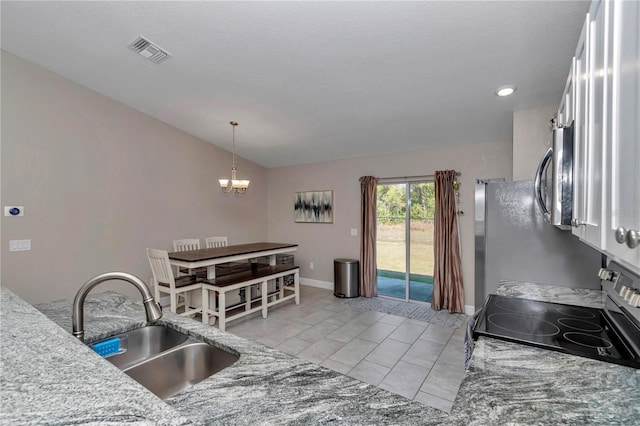 kitchen featuring vaulted ceiling, appliances with stainless steel finishes, sink, light tile patterned floors, and an inviting chandelier