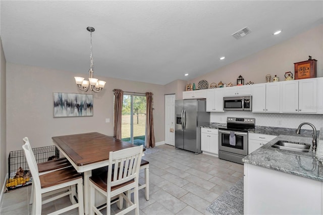 kitchen featuring vaulted ceiling, sink, white cabinets, hanging light fixtures, and stainless steel appliances