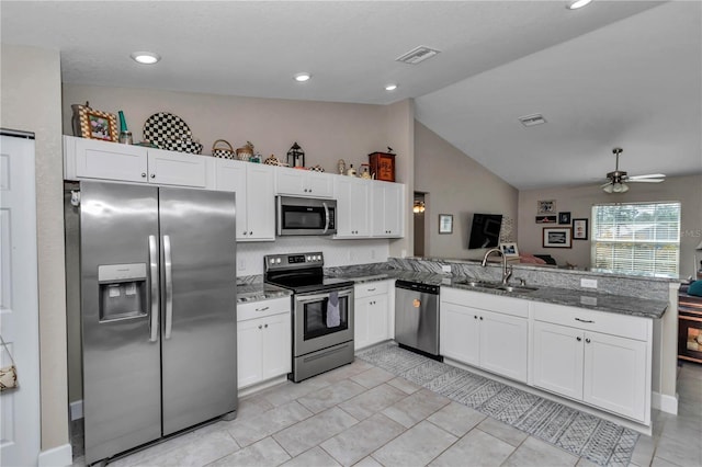 kitchen with sink, appliances with stainless steel finishes, white cabinetry, kitchen peninsula, and dark stone counters