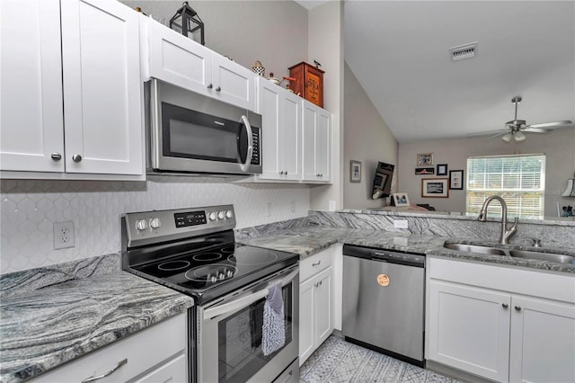 kitchen featuring appliances with stainless steel finishes, sink, white cabinets, kitchen peninsula, and light stone countertops