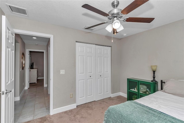 bedroom featuring light colored carpet, a textured ceiling, ceiling fan, and a closet